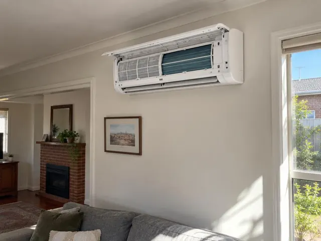 Clean split system indoor unit with open front panel and visible filters on a living room wall in Mile End