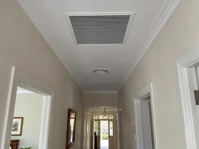 Ceiling return-air grille in a narrow hallway with cream walls and white trim in Parkside